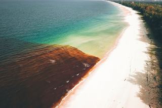 Plage de sable sombre et mer calme sur la côte sous-le-vent de Bouillante